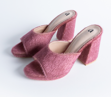 a pair of fuzzy pink slide-on shoes with a peep toe and a block heel