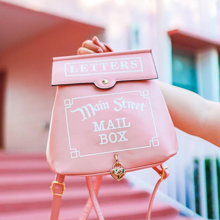 a light pink back pack designed to look like a mail box that says "main street mail box" on it