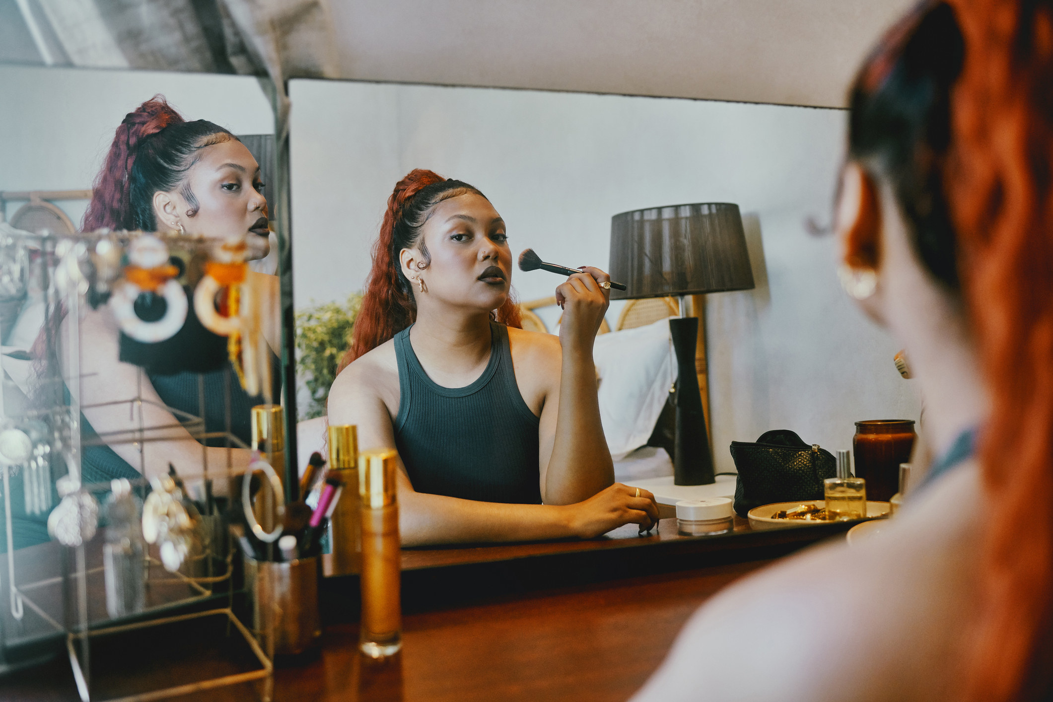 Shot of a beautiful young woman doing her makeup while sitting in front of the mirror
