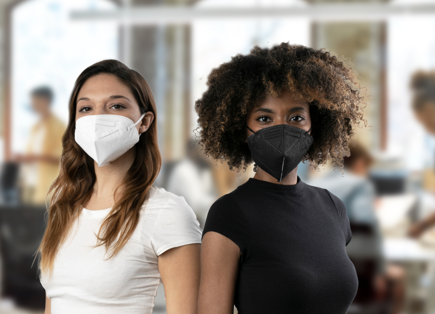 Two people stand side-by-side in an office while wearing masks
