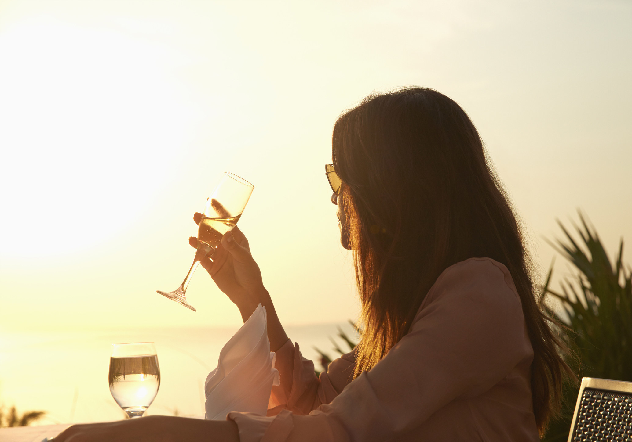 Woman drinking champagne at sunset dinner outdoors
