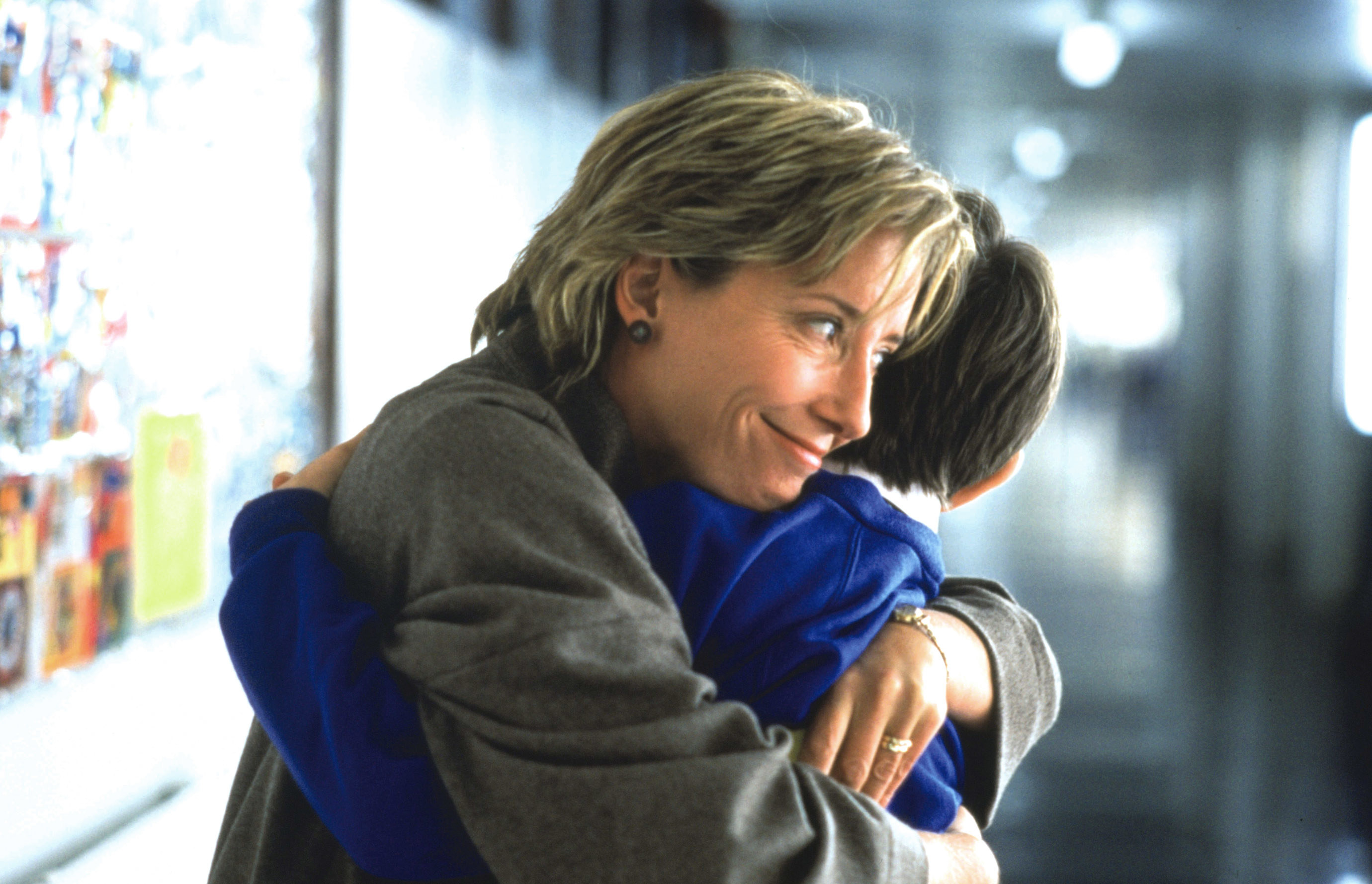 A younger Emma hugging a child during a movie scene