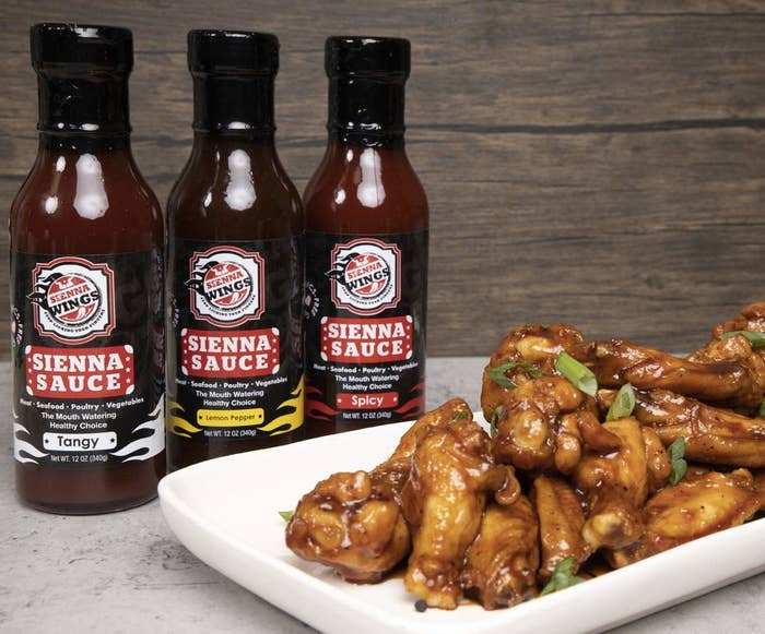 three bottles of Sienna Sauce sitting next to a plate of wings