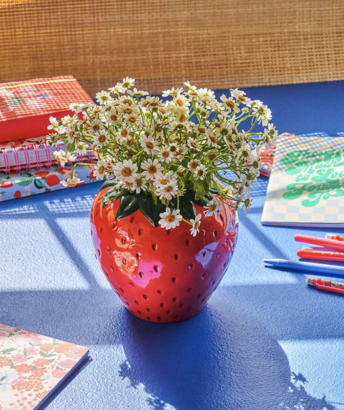 strawberry vase with daisies in it