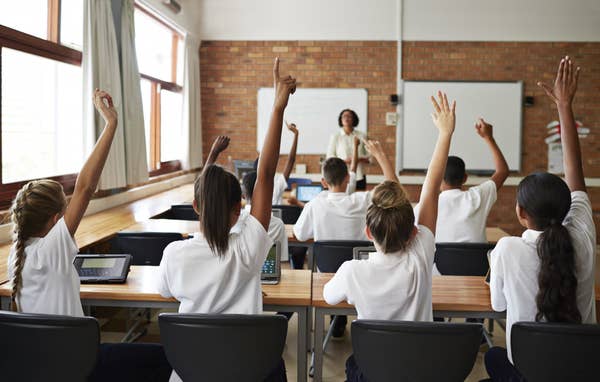 Students raise their hands in a classroom