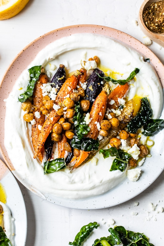 A yogurt bowl topped with roast carrots, chickpeas, and kale.