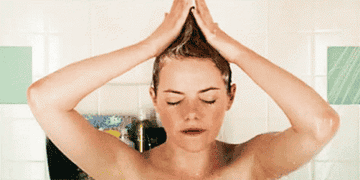 A woman is singing in the shower whilst she shampoo&#x27;s her hair up into a &#x27;V&#x27; shape