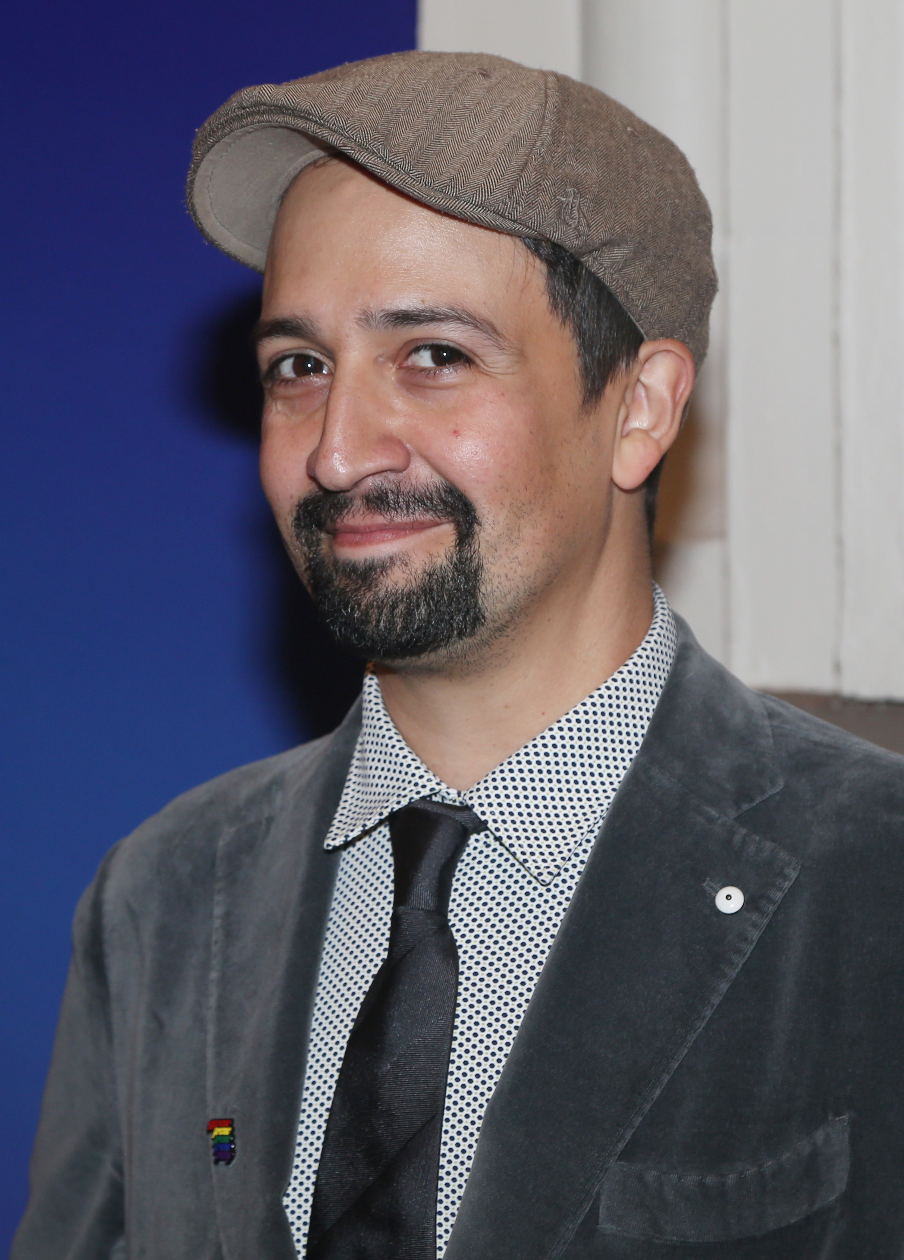 Miranda smiles while wearing a newsboy cap