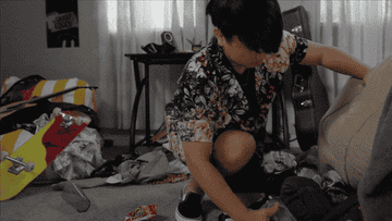 A young boy tidies his clothes away
