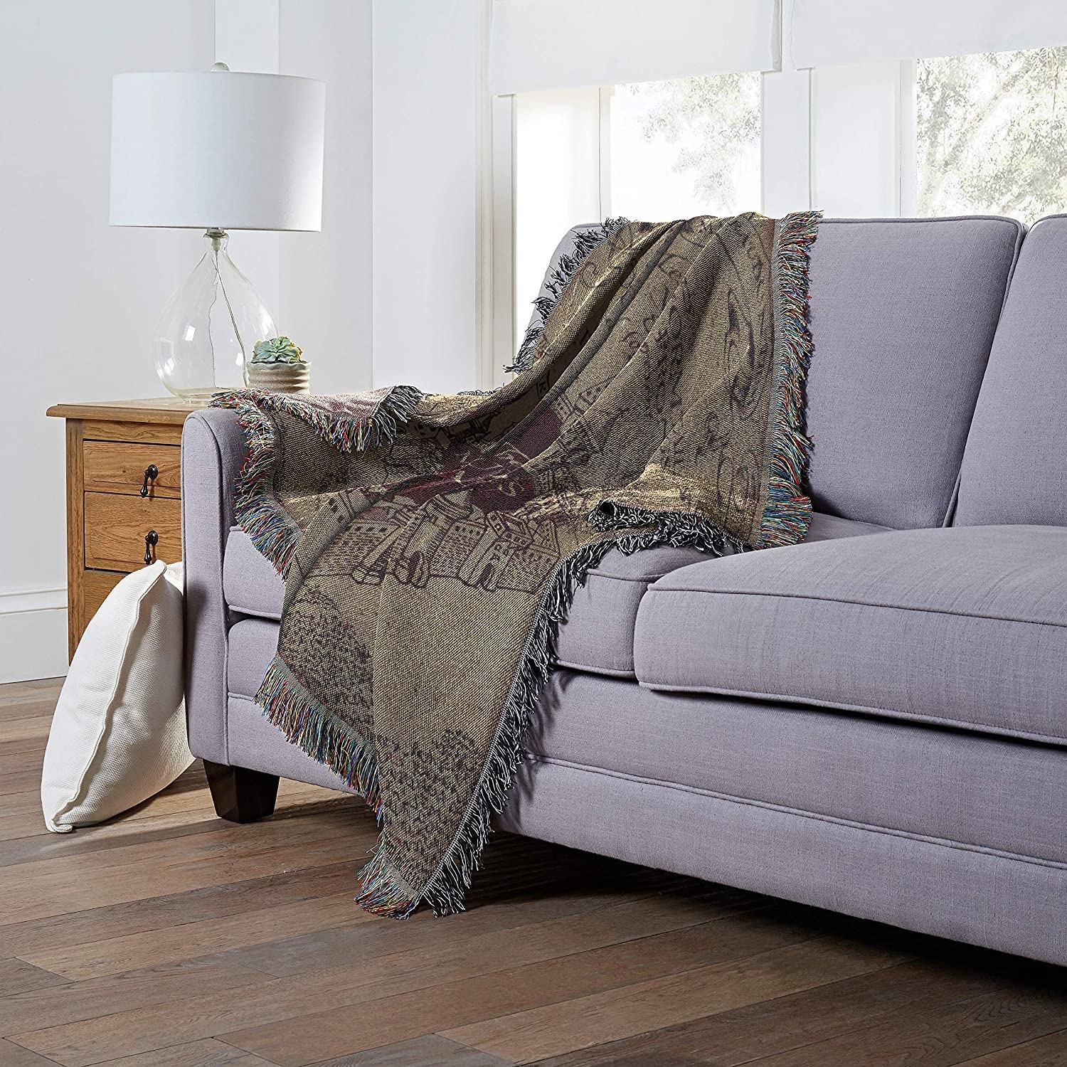 The tapestry blanket thrown over the arm of a couch in a trendy living room