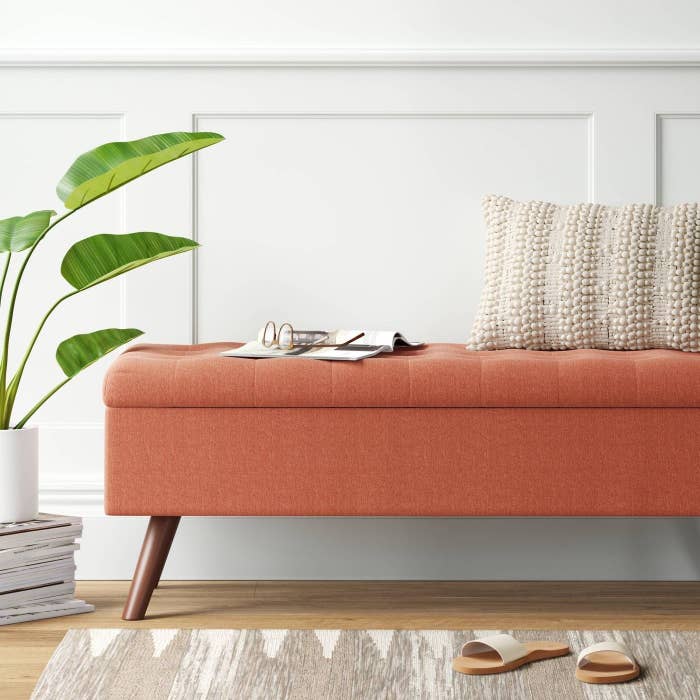the orange upholstered ottoman in a decorated space