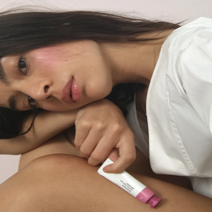 a model wearing cloud paint and holding a tube of it