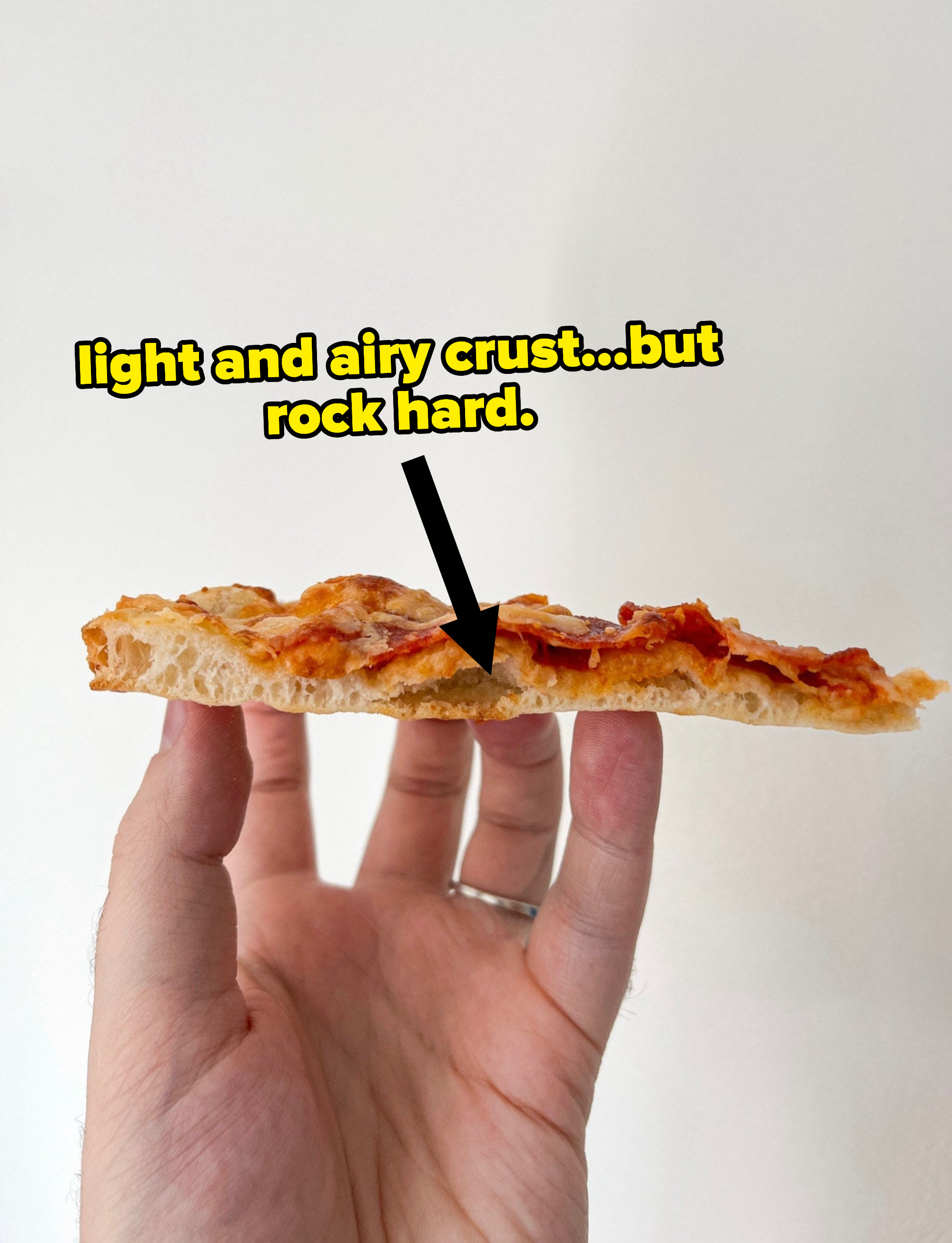 Cross-section of cooked pizza with bubbly crust, text says &quot;light and airy crust but rock hard)