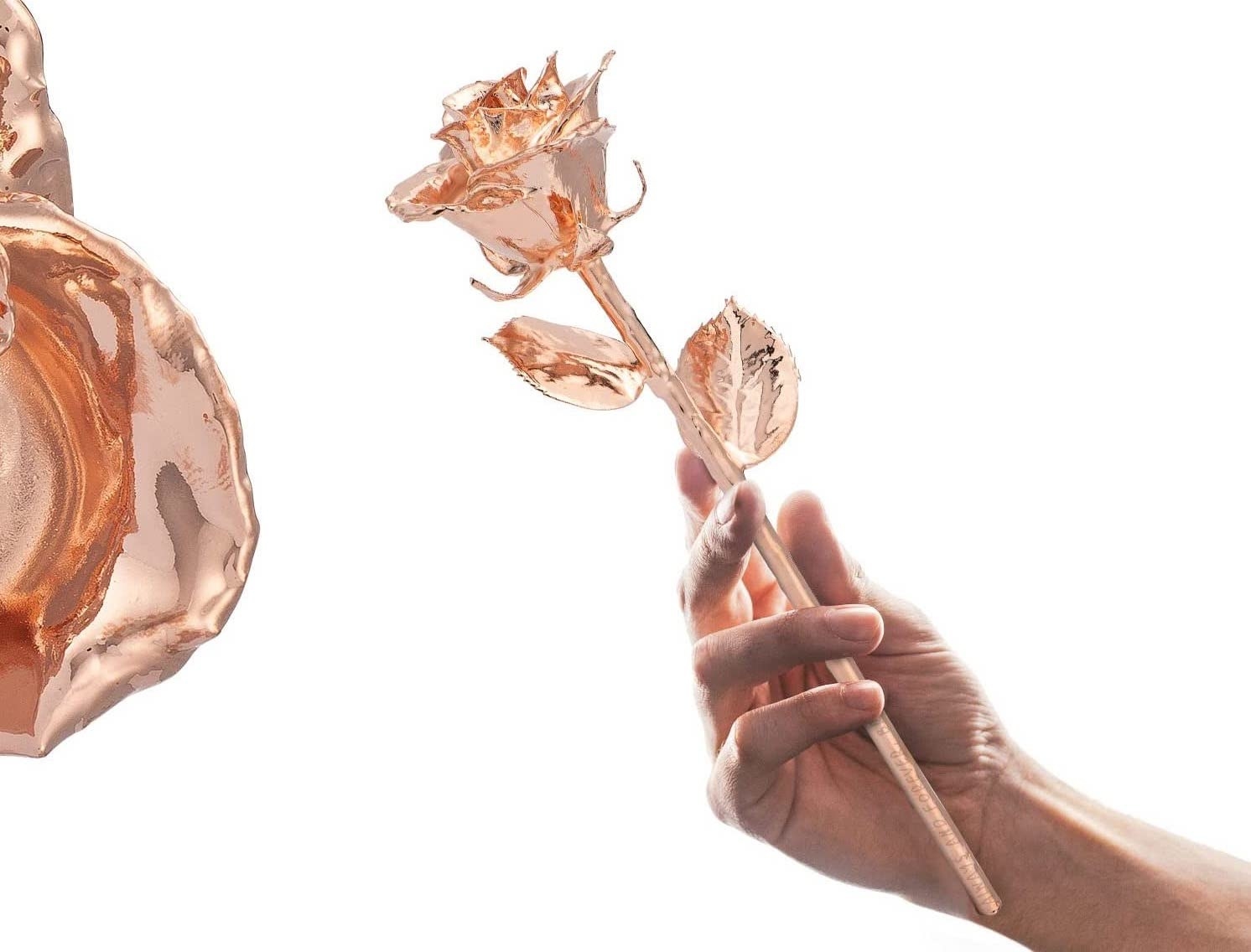 A person&#x27;s hand holding up one of the metallic roses