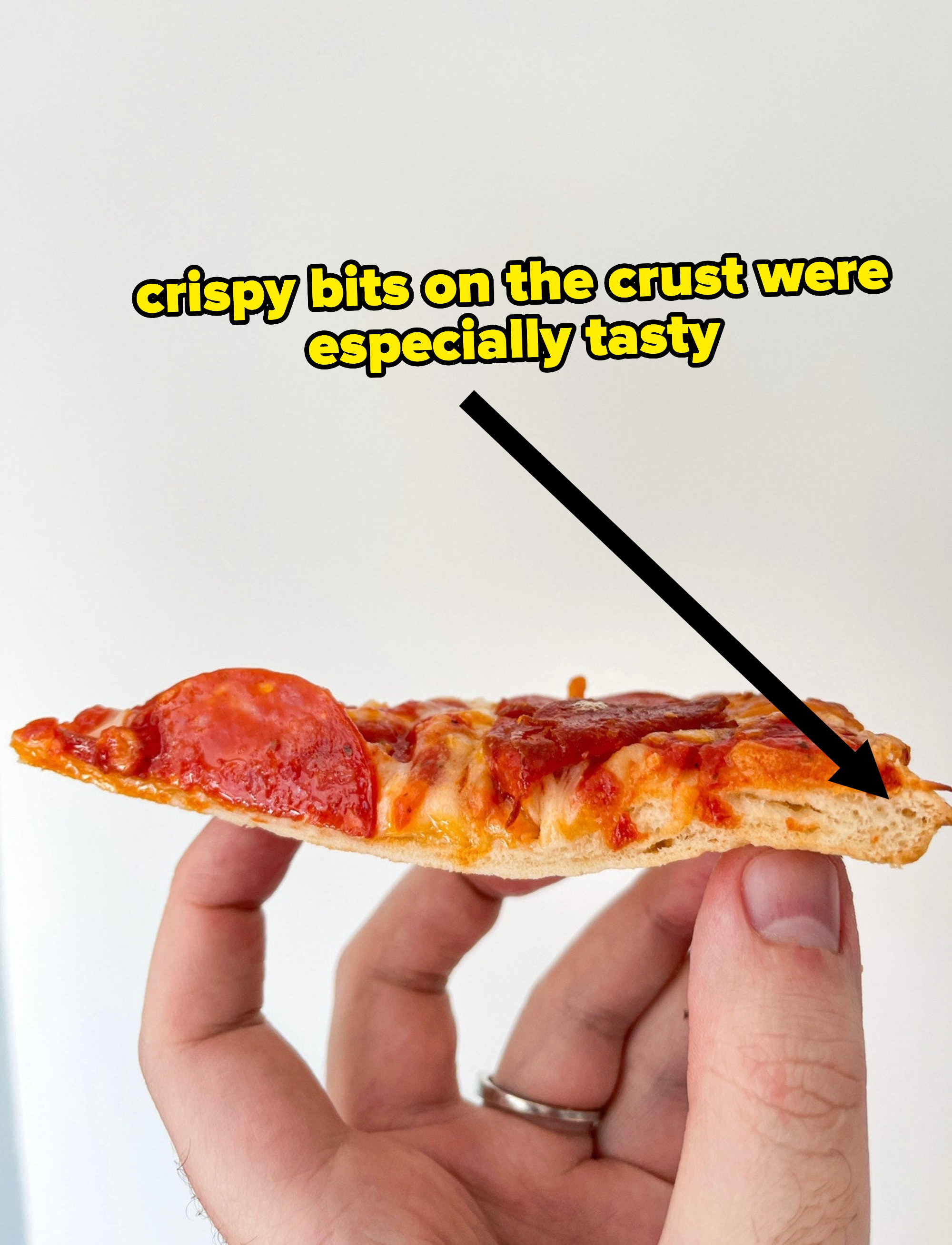 Author holding cross-section of pizza with text &quot;the crispy bits on the crust were especially tasty&quot;
