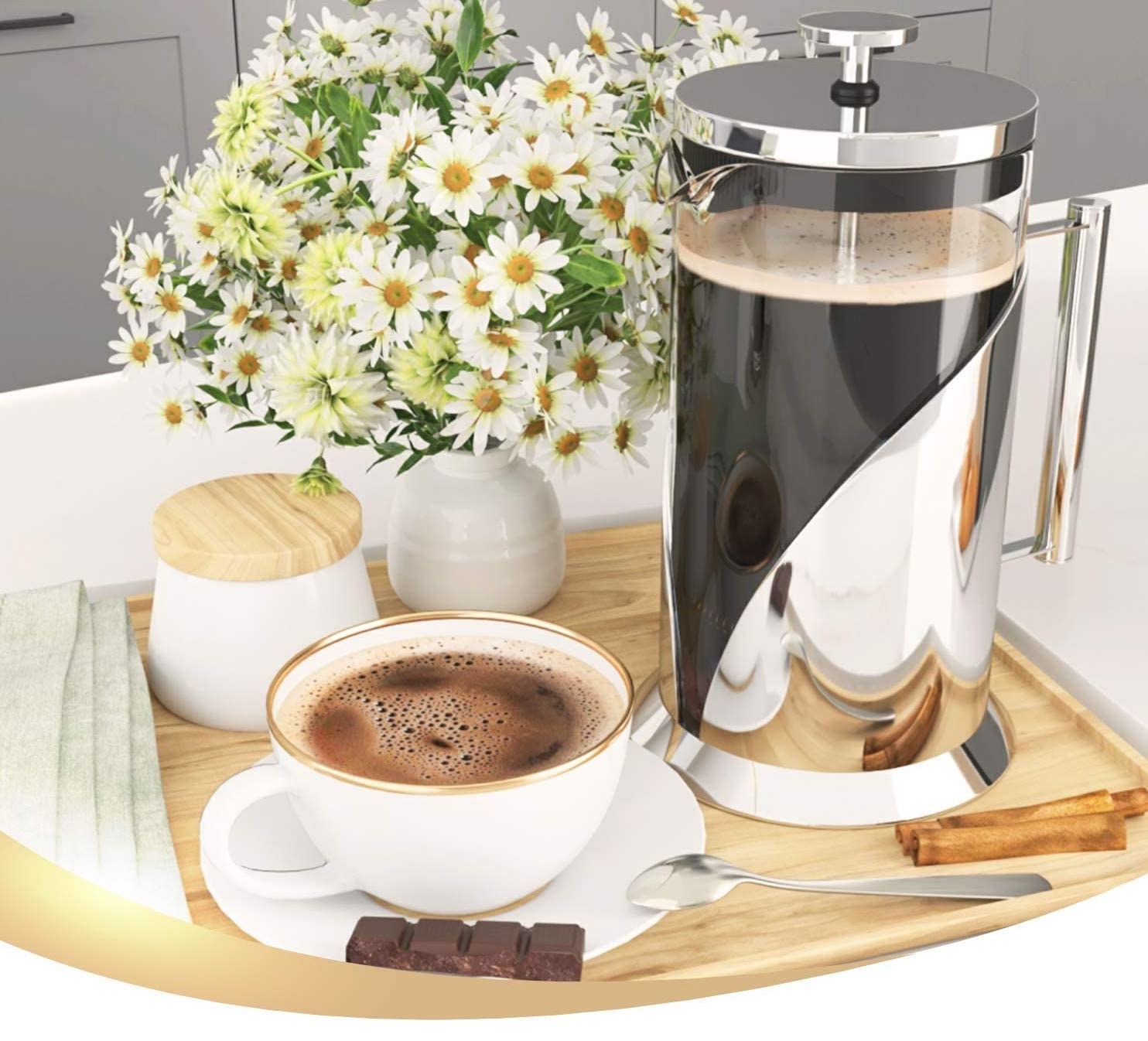 The french press on a tray with flowers and a cup of coffee