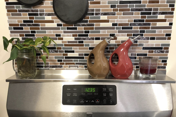 A customer review photo of the shelf on top of their stove holding some decor