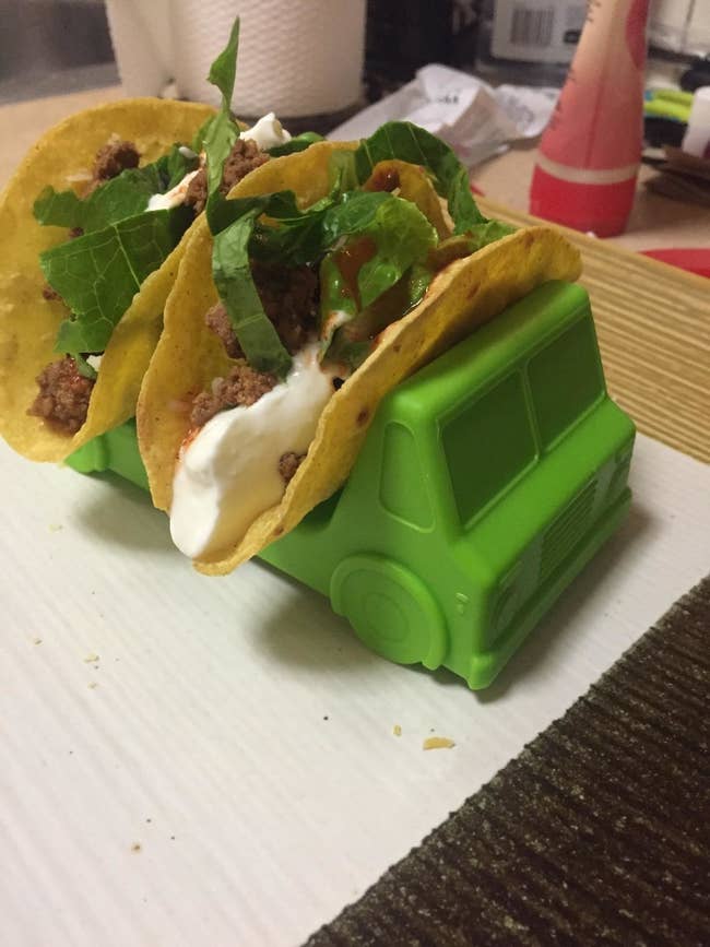 reviewer photo of a green plastic truck with two spaces to put taco shells in each