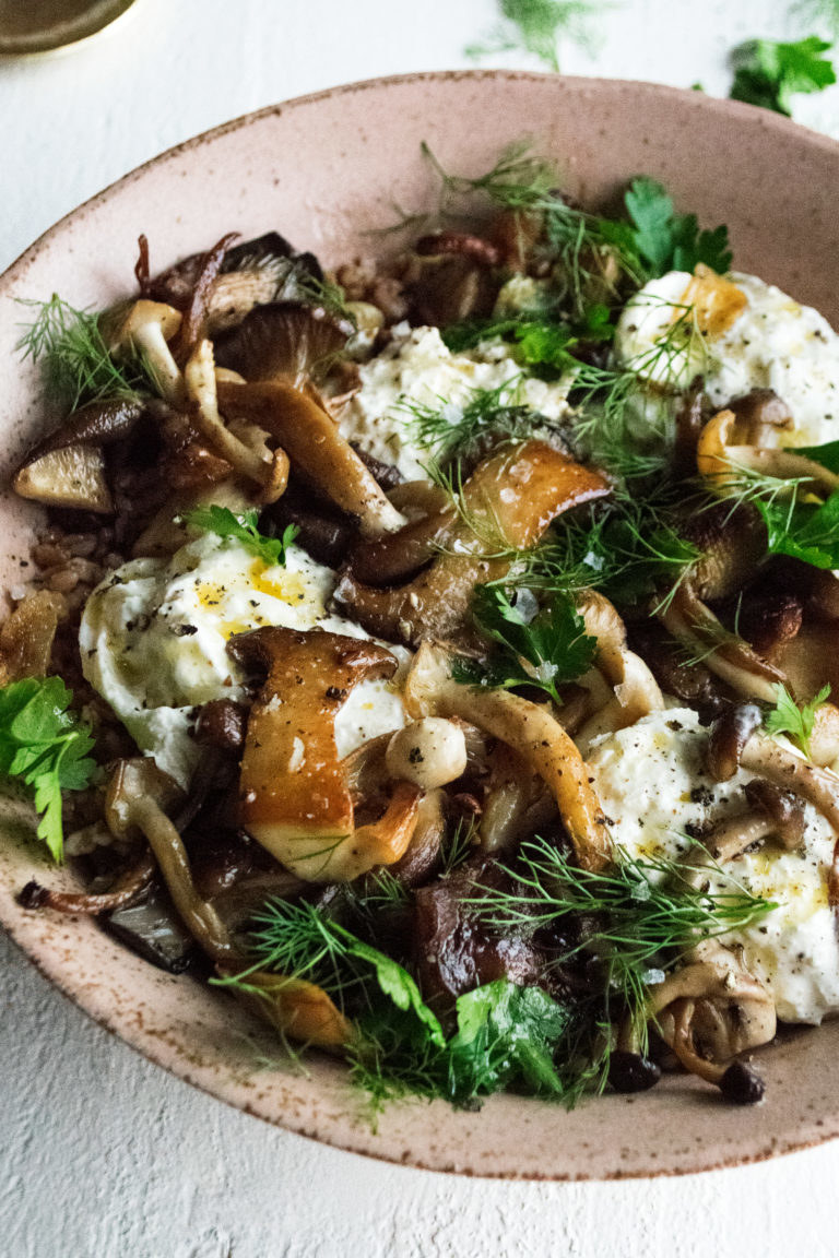A bowl of mushrooms with burrata and herbs