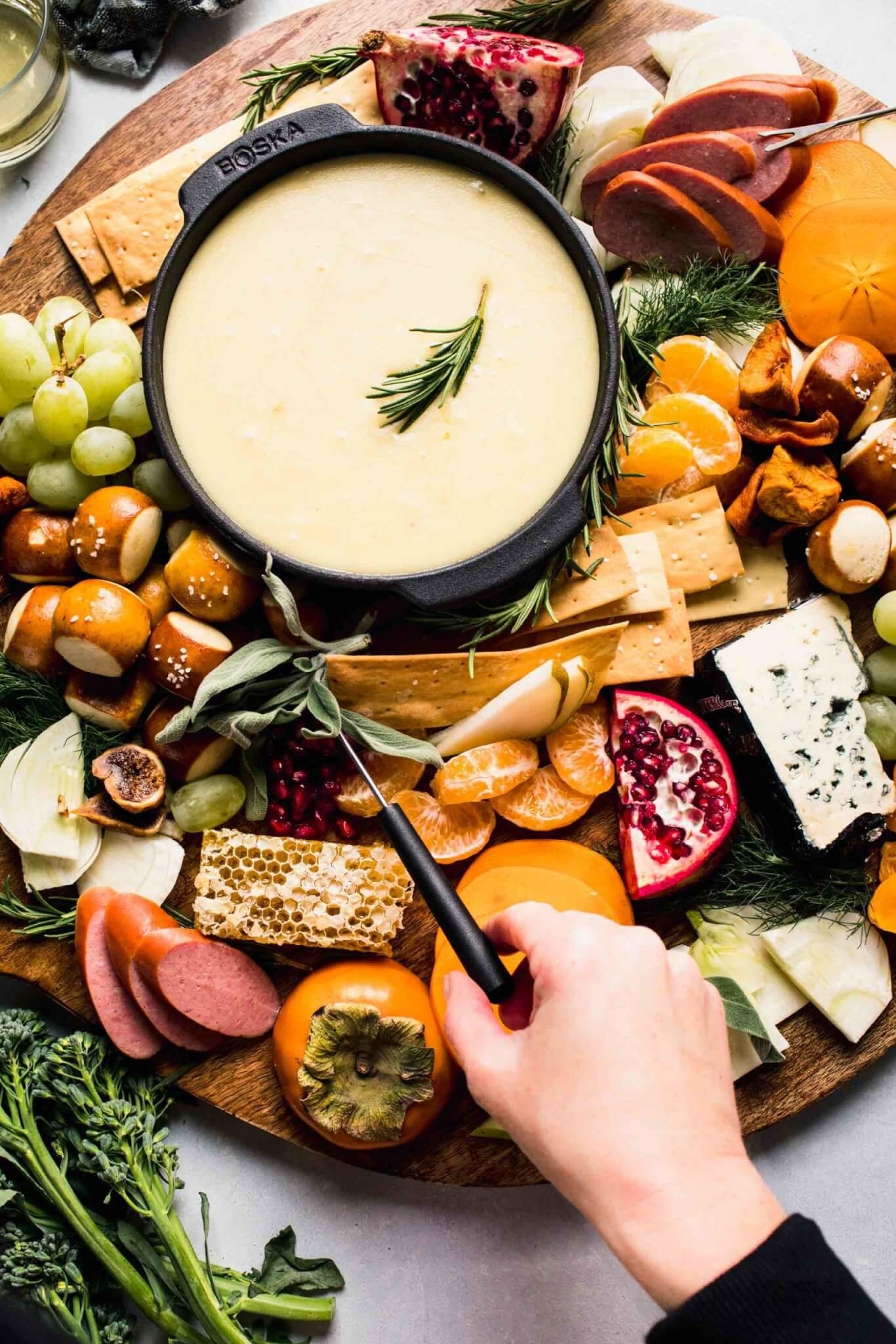 Cheese fondue with vegetables, crackers, bread, and fruit for dipping