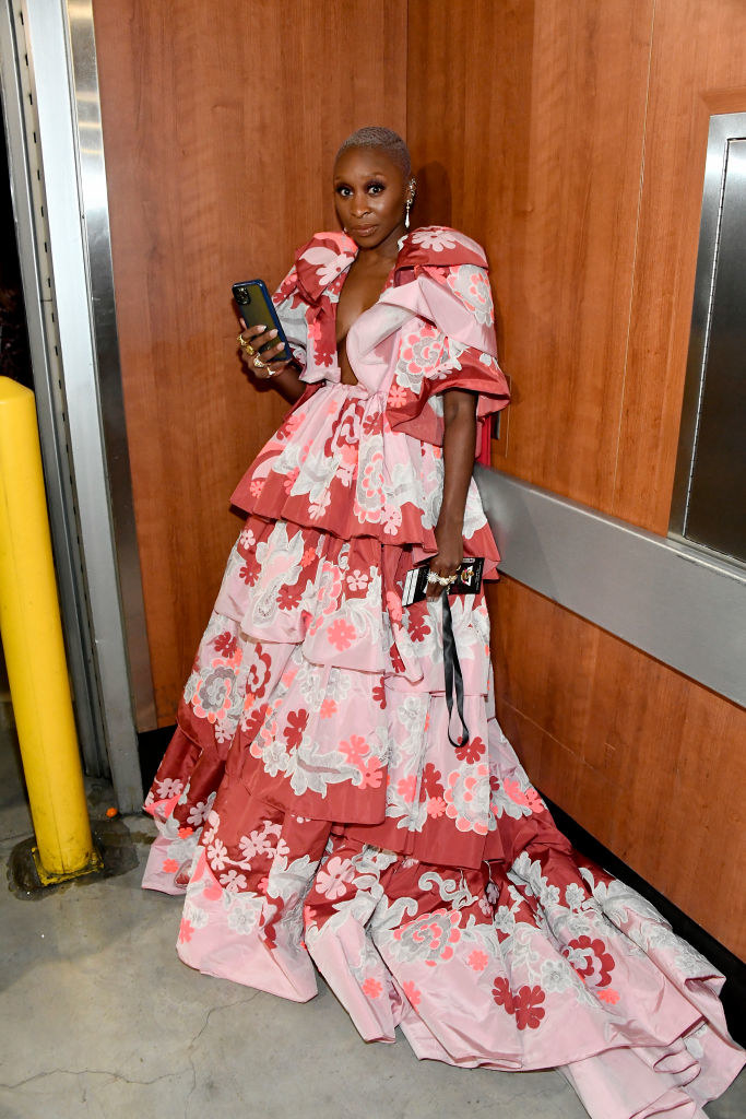 Erivo in pink and red puff-sleeved floral gown, holding her phone