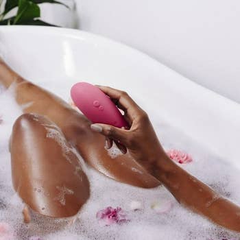Model in bathtub holding pink suction vibrator