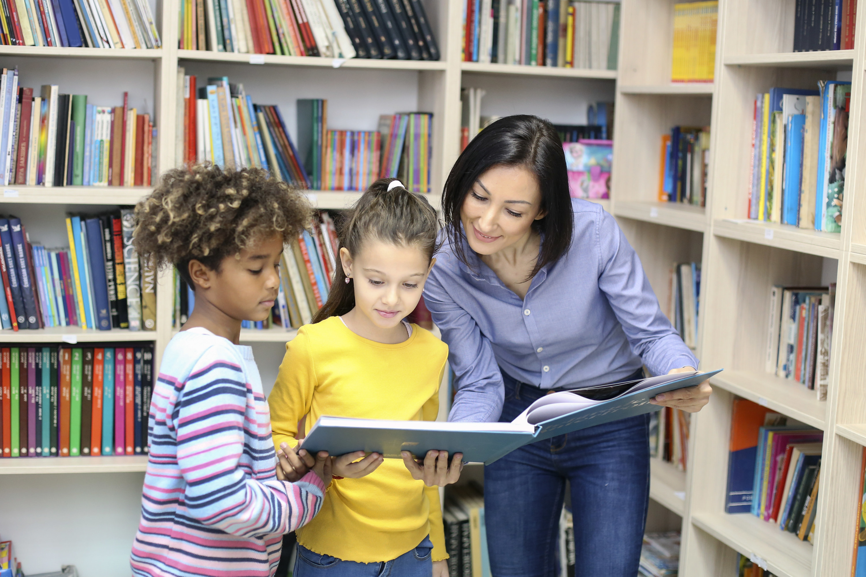 Librarian showing a book to two young children
