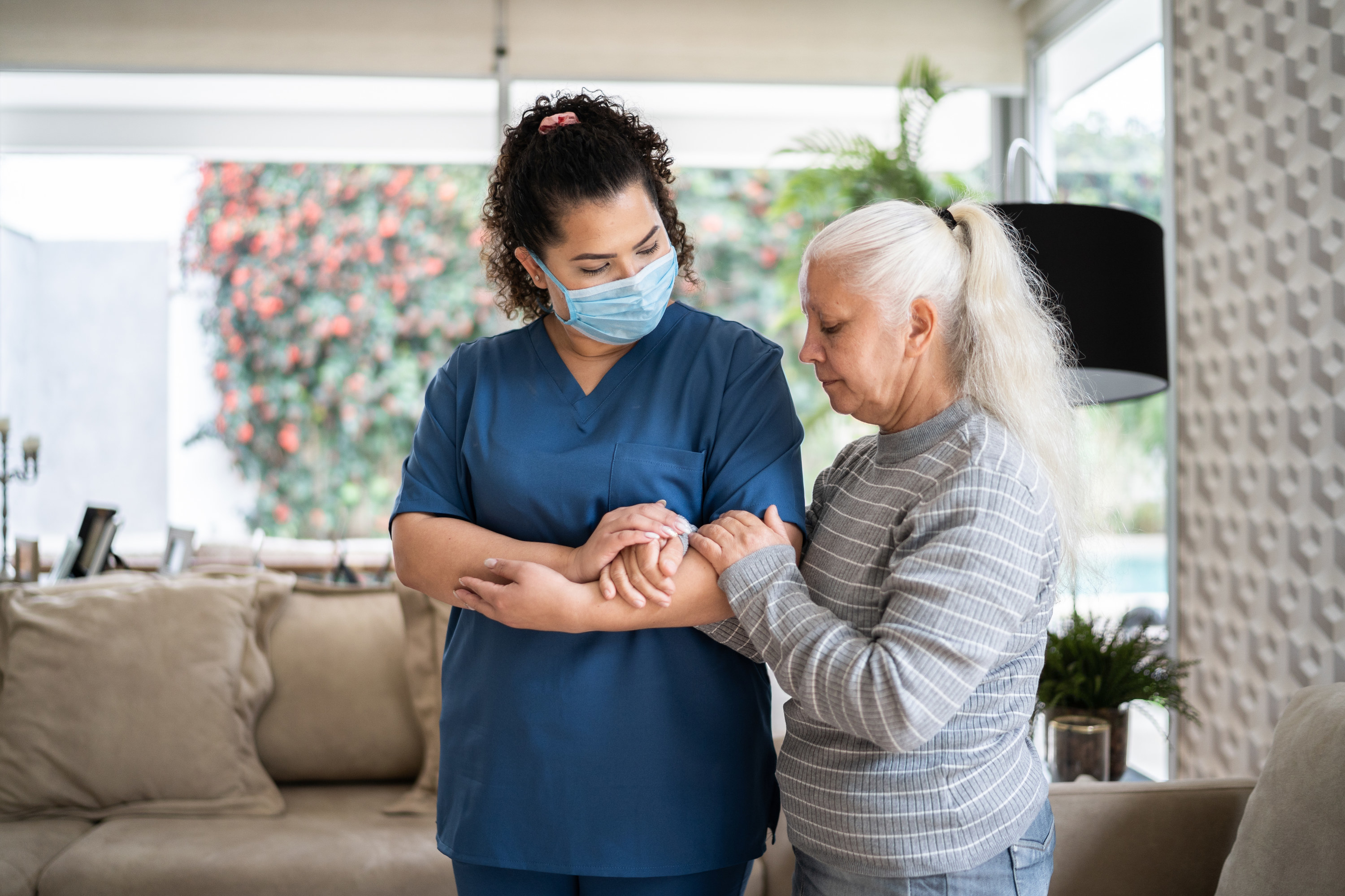 Patient holding on to a therapist&#x27;s arm as they walk together