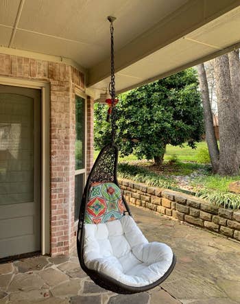 reviewer photo of the wicker chair hanging in a covered patio