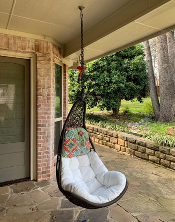 reviewer photo of the wicker chair hanging in a covered patio