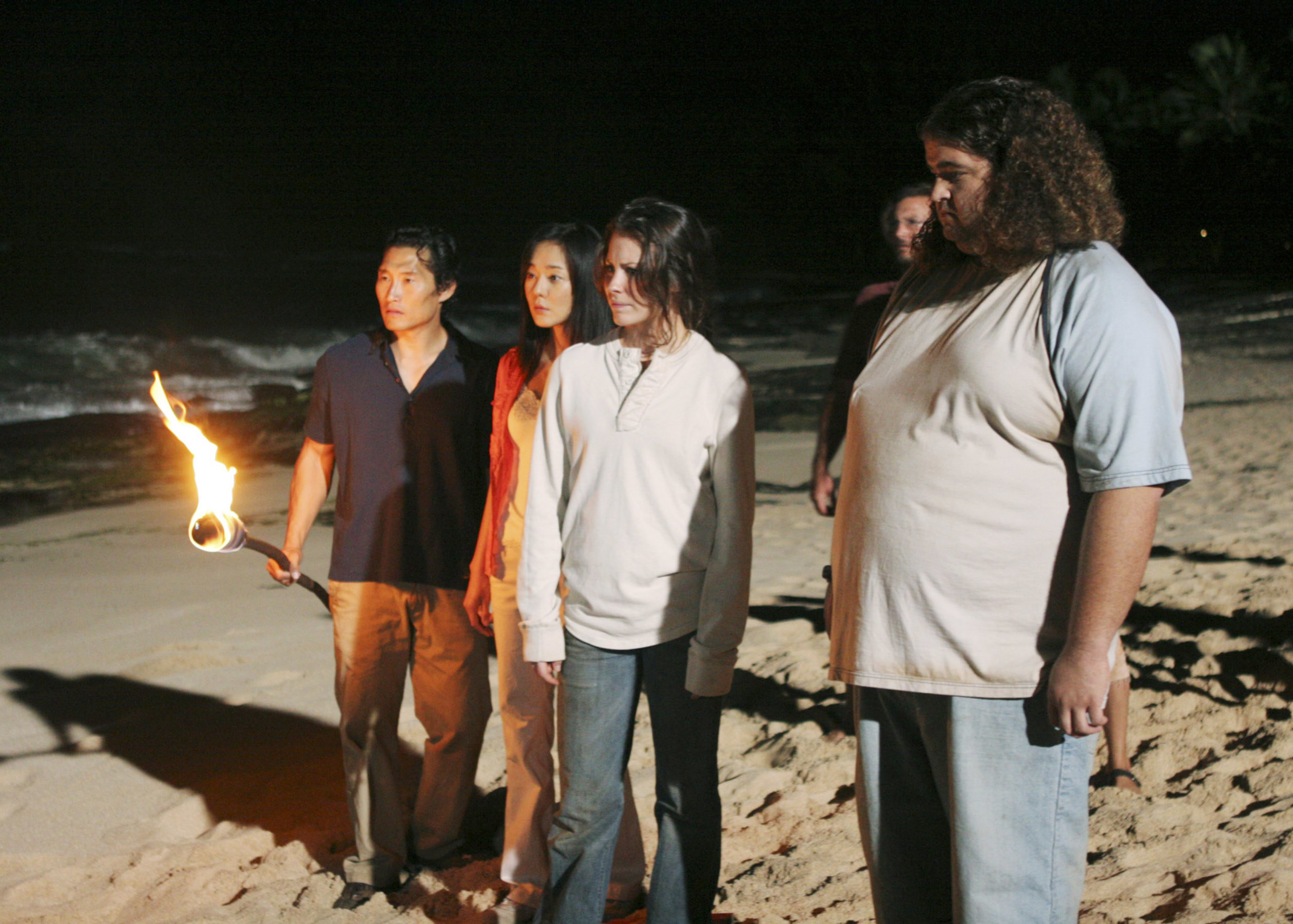 some of the cast on the beach, with Daniel Dae Kim holding a torch