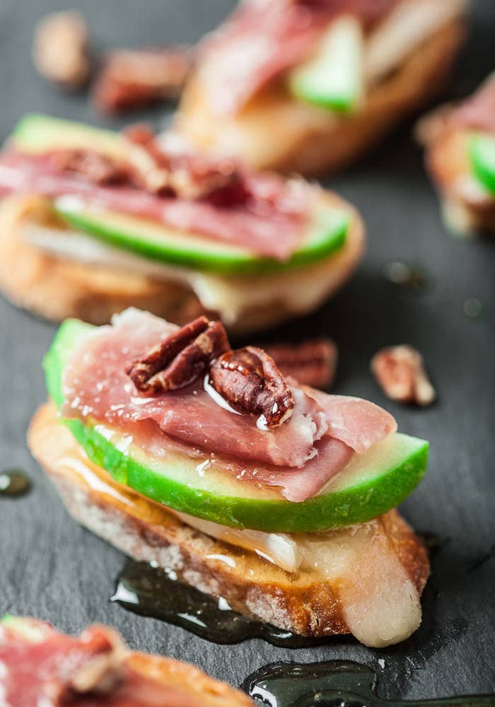 Crostini topped with Brie cheese, prosciutto, and sliced apple