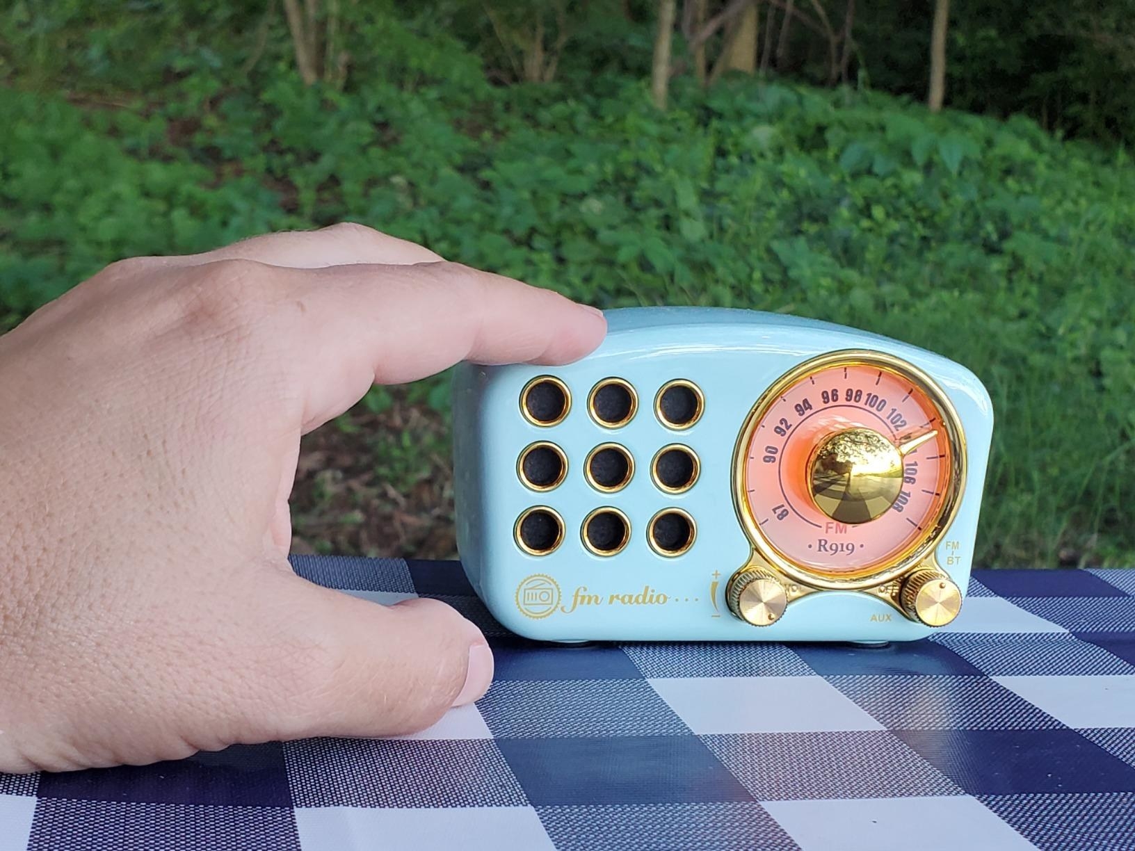 hand touches tiny blue retro radio