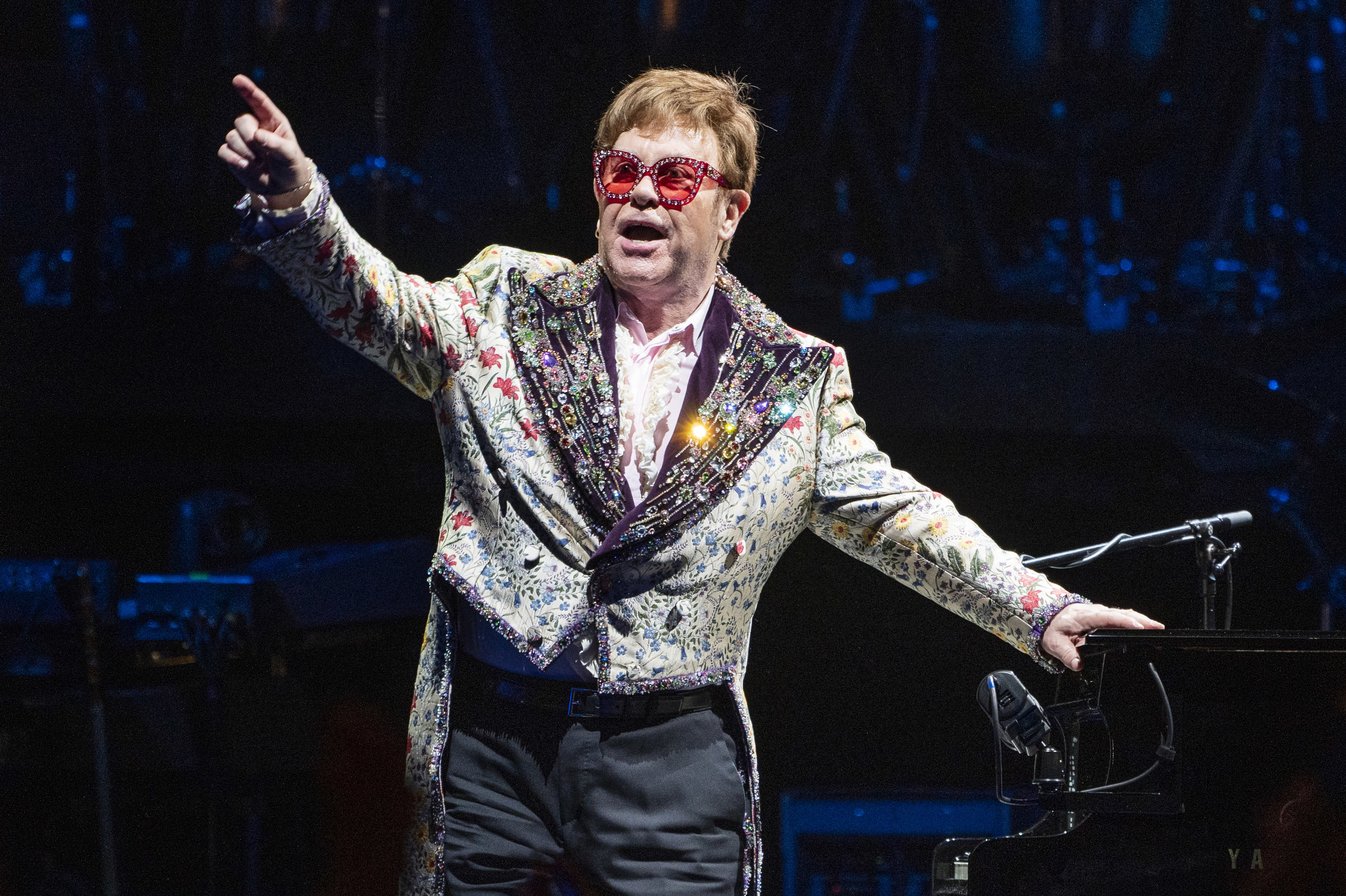 Elton leans on his piano and points to the crowd