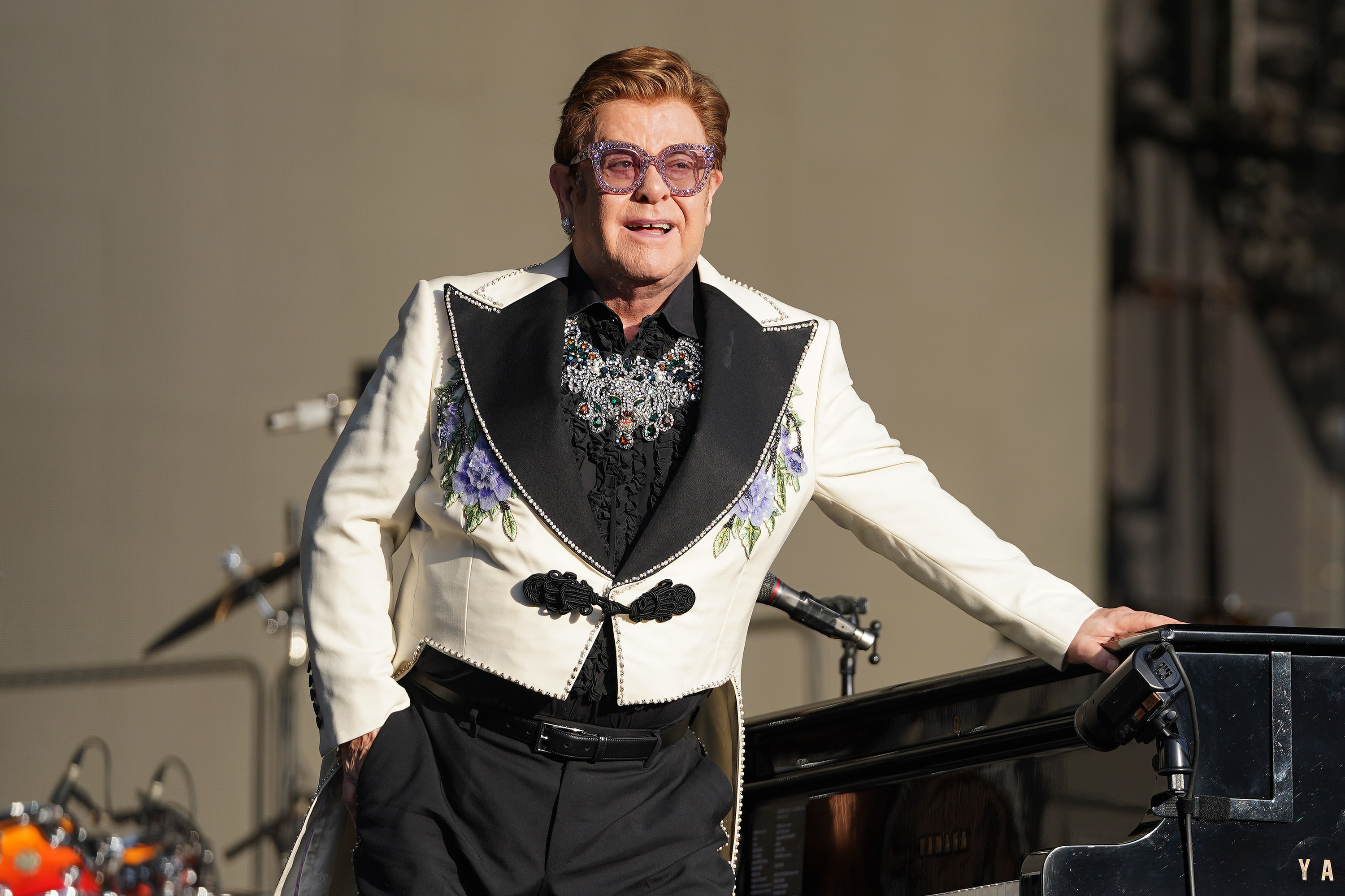 Elton leans on his piano and smiles