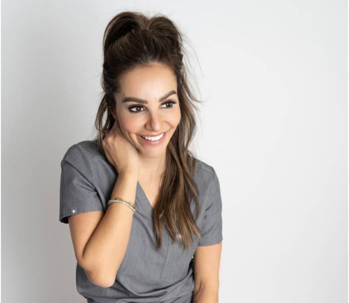 Jody smiling in a headshot, resting her hand on the side of her neck