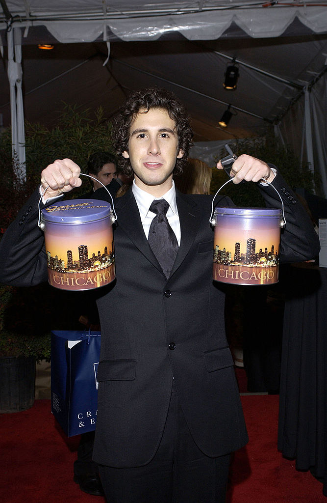 josh in a suit with popcorn tins that have the nyc skyline on it