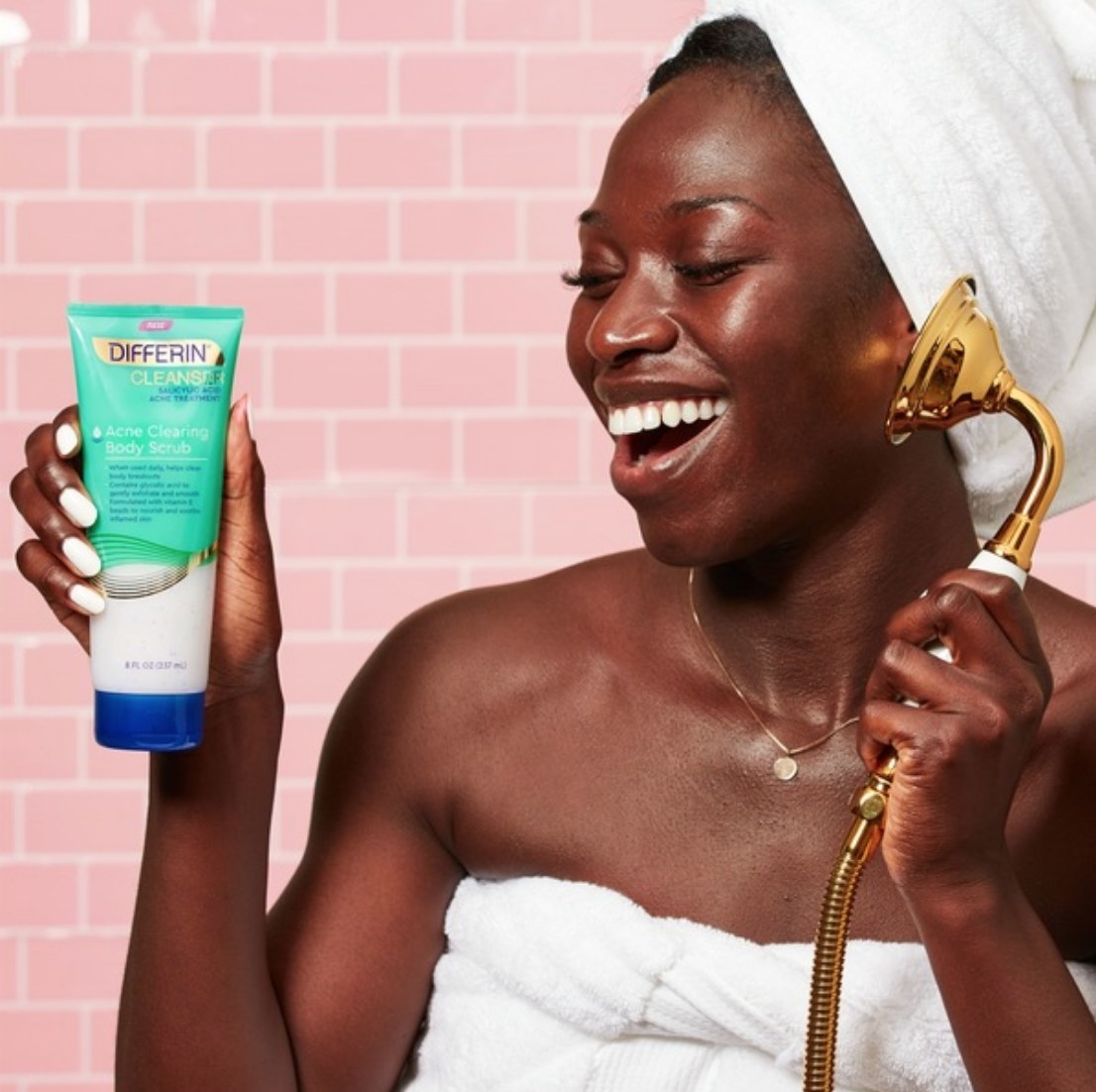 A model holding a bottle of acne-clearing body scrub in the shower
