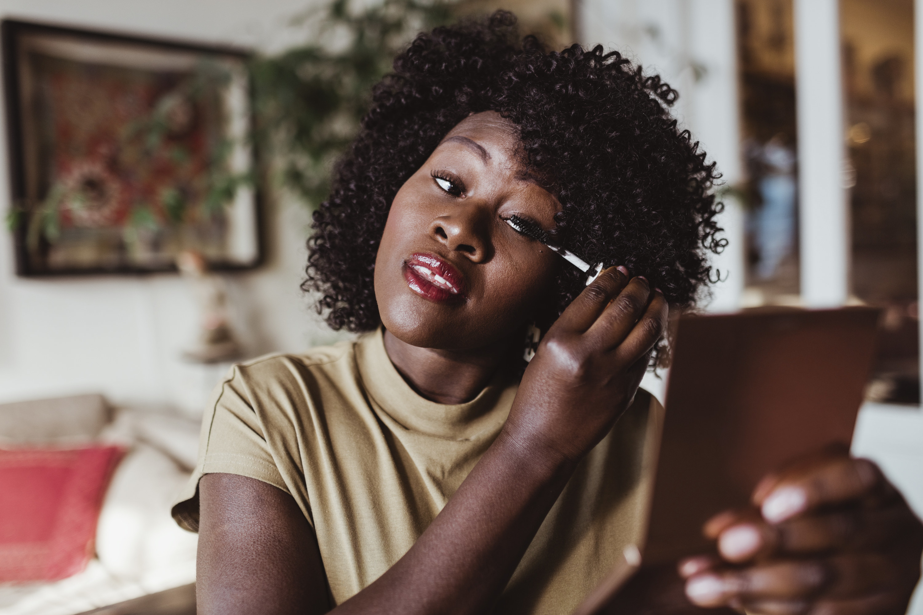 A woman applying eye makeup while looking in a compact mirror