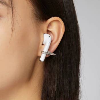silver ziptie-style earrings holding an airpod in a models ear