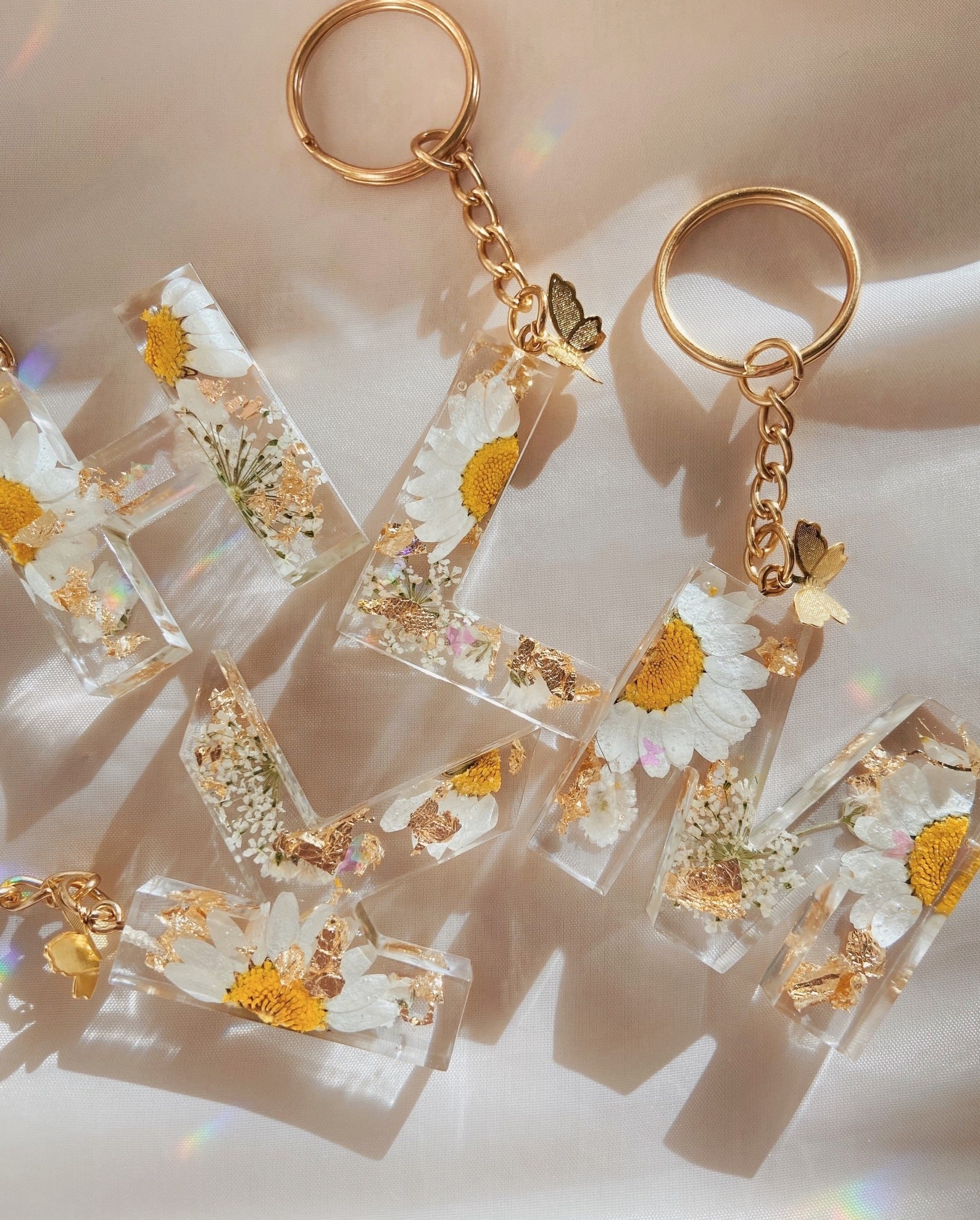 the daisy keychains with butterfly charms in the letters h, k, l, and m
