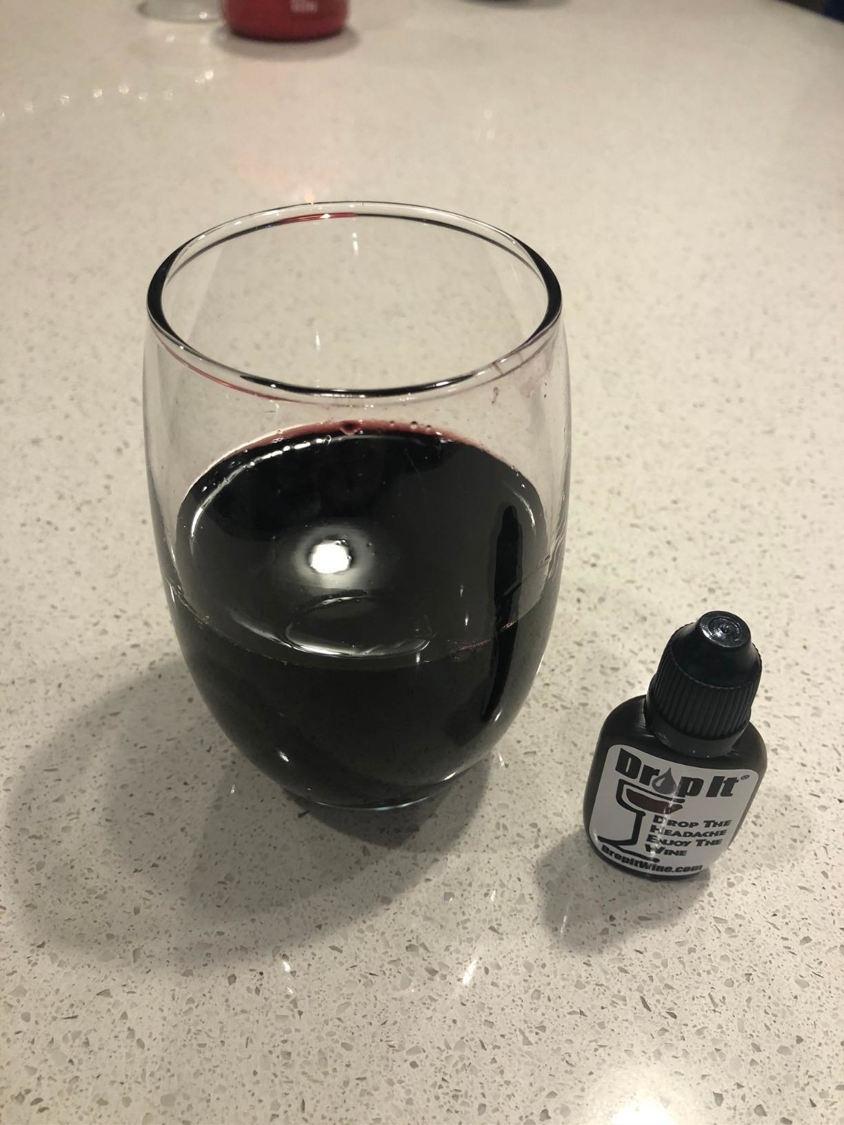 reviewer image of a glass of red wine next to a bottle of Drop It