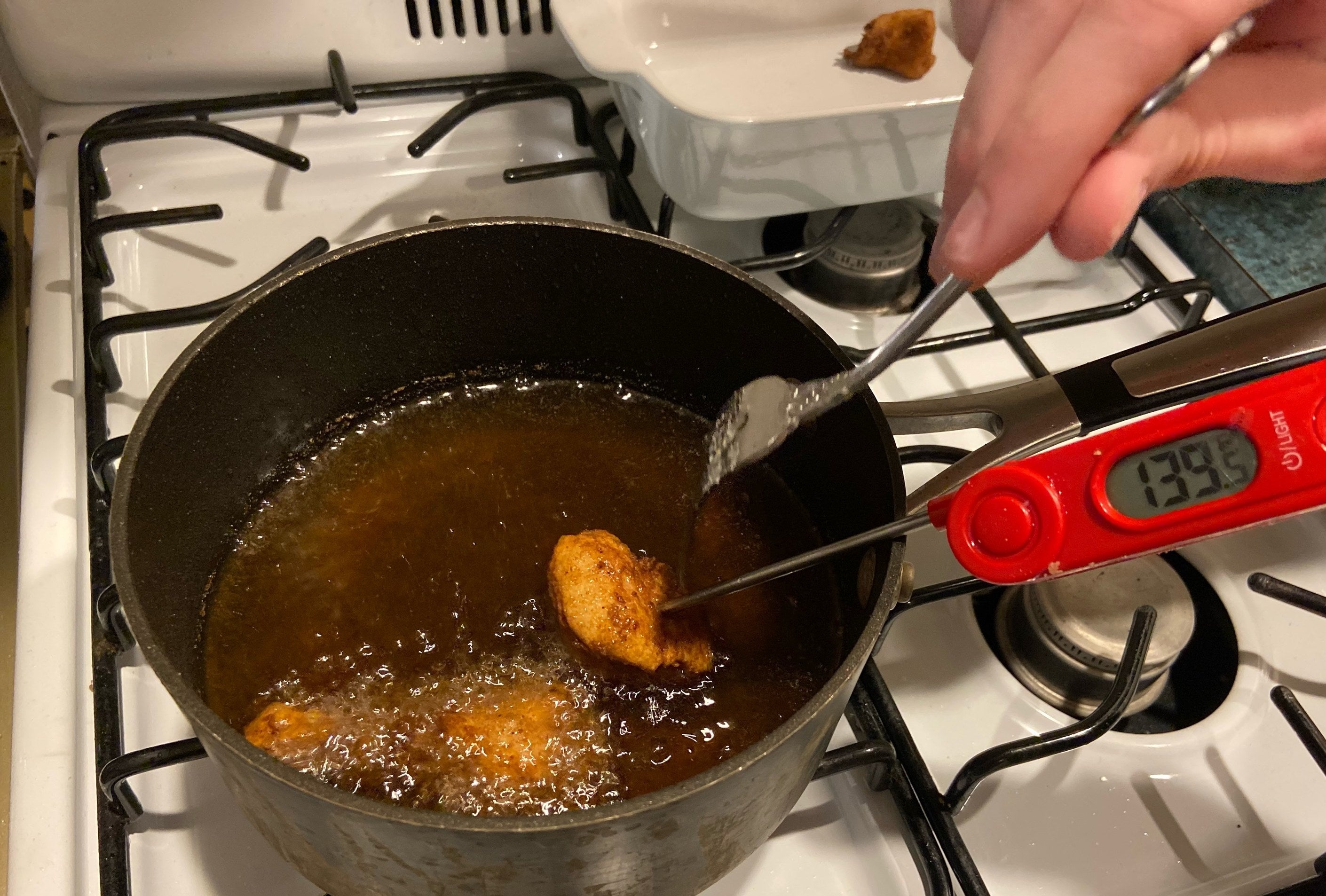 Someone using a meat thermometer to check the internal temperature of the chicken.