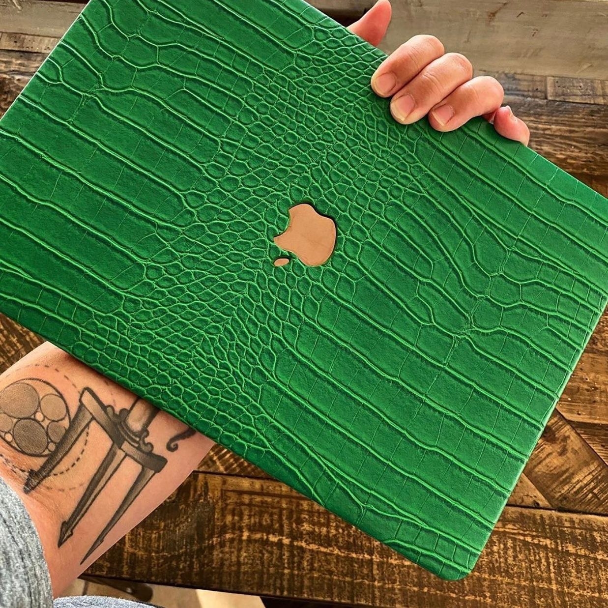 the CEO of Chic Geeks holding a laptop with the emerald faux crocodile cover