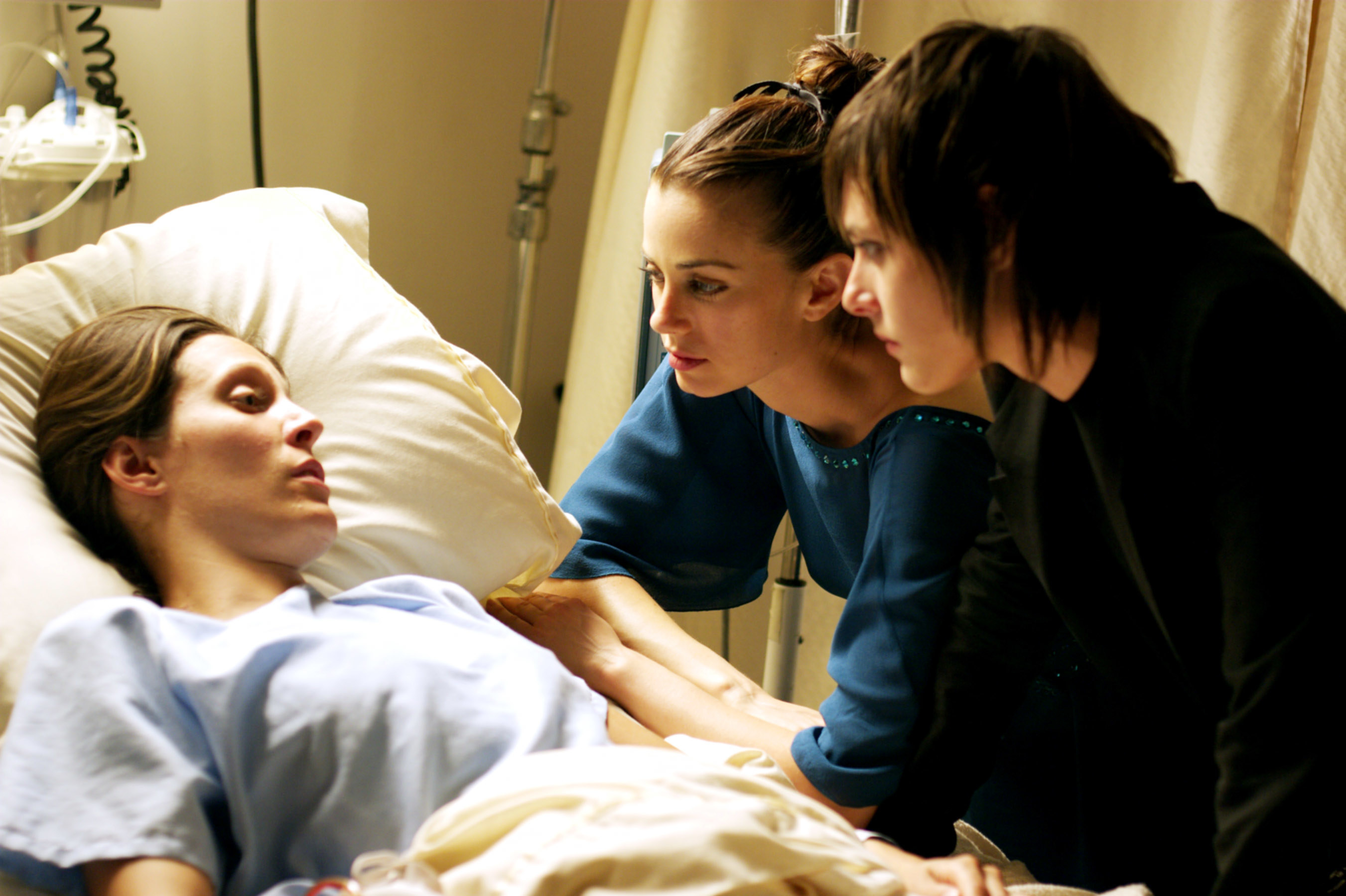 Dana in the hospital bed with her friends beside her