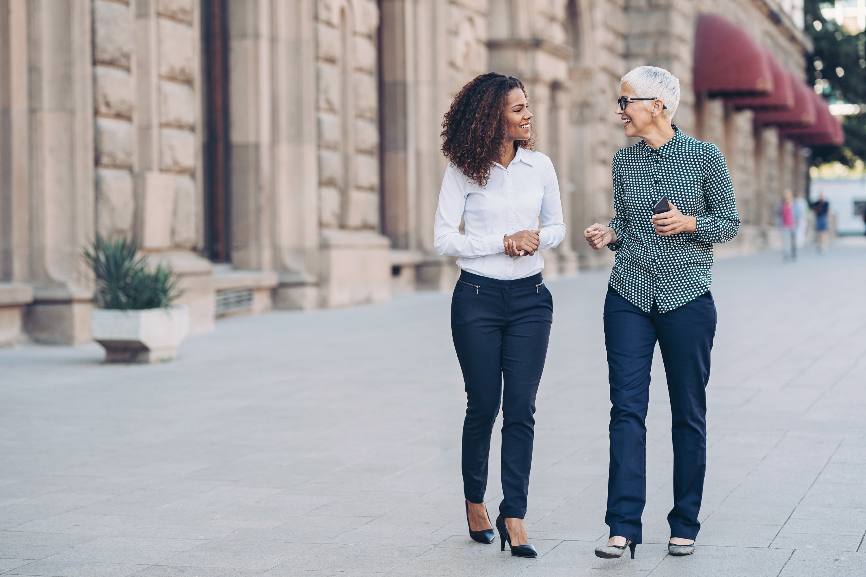 Two women walking together and talking outdoors in the city