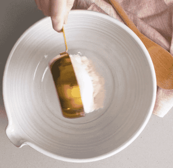 gif of someone using the gold measuring cups to pour flour and sugar into a mixing bowl