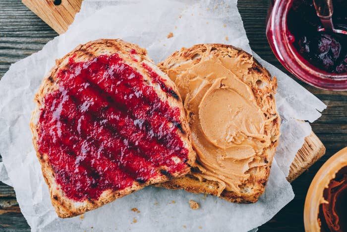 Peanut butter toast with jam on wooden background.
