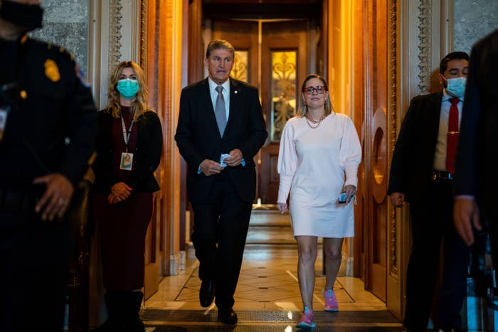 Senators Joe Manchin and Kyrsten Sinema walk through a hallway