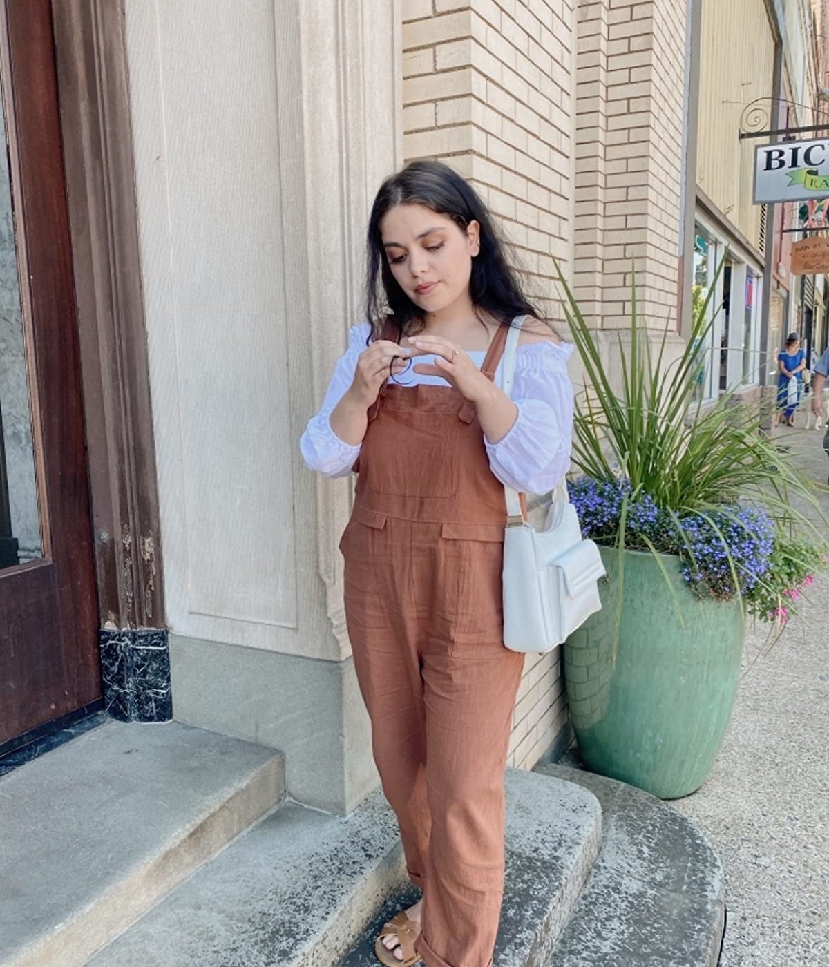 reviewer outdoors wearing the brown overalls in size small